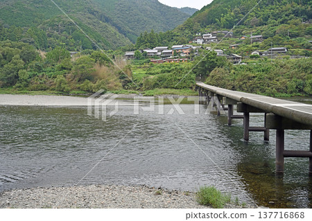 The Iwama Submersible Bridge on the Shimanto River and the rural village landscape spreading across the opposite bank. The Iwama Submersible Bridge on the Shimanto River and the rural village landscape spreading across the opposite bank. 137716868
