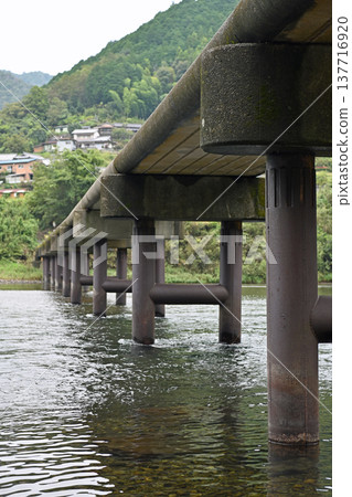 The powerful bridge piers supporting the Iwama Submersible Bridge on the Shimanto River and the road that follows The powerful bridge piers supporting the Iwama Submersible Bridge on the Shimanto River and the road that follows 137716920