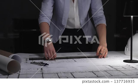 Female architect working on blueprints, measuring building plans at night, designing new construction project. Business and architect people concept 137716935