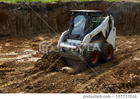 Heavy machinery moves dirt at a construction site with a clear focus on ground leveling and preparation for building Heavy machinery moves dirt at a construction site with a clear focus on ground leveling and preparation for building 137717016