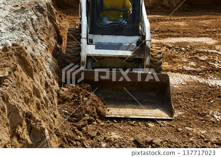 The excavator works to clear the soil and move it out of the excavation at the construction site The excavator works to clear the soil and move it out of the excavation at the construction site 137717023