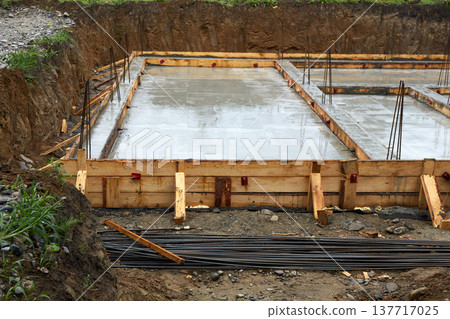 A concrete foundation is being poured on the construction site. Wooden formwork is used.  137717025