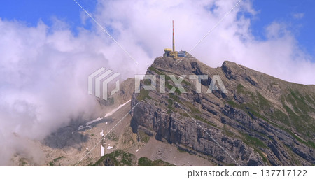 Mountain peak with building and antenna surrounded by clouds during the day in clear weather Mountain peak with building and antenna surrounded by clouds during the day in clear weather 137717122