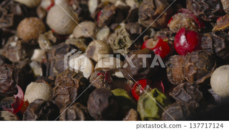 Various colorful spices and peppercorns arranged together in a bowl on a wooden table during daylight 137717124