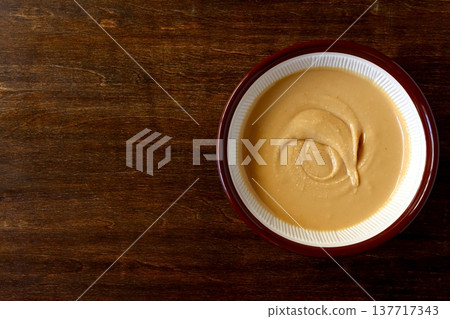 Homemade peanut butter ground in a mortar and pestle, shown in the background of the table. 137717343