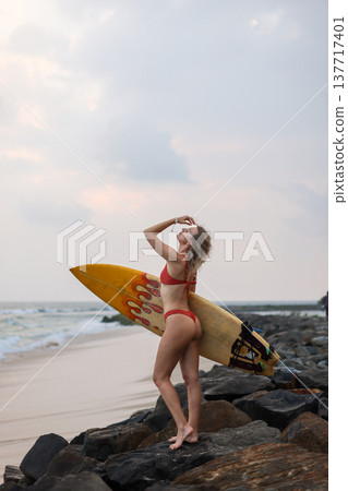 Coastal Surfer Checks Beach Swell Carefully. Energetic Surfer Prepares To Ride Incoming Waves At Dawn Coastal Surfer Checks Beach Swell Carefully. Energetic Surfer Prepares To Ride Incoming Waves At Dawn 137717401