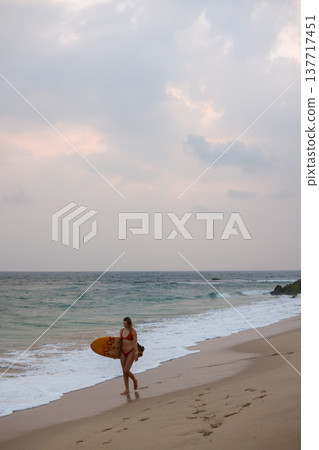 Beach Traveler Pondering. Distant Horizon Guides Lone Explorer Through Gentle Waves And Soft Glow 137717451