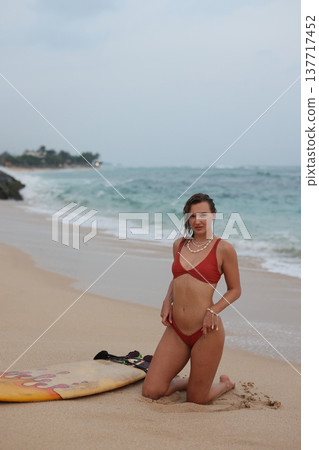 Woman On Beach Preparing Gear. Relaxed Woman In Summer Attire By Coastal Rocks With Surfboard 137717452