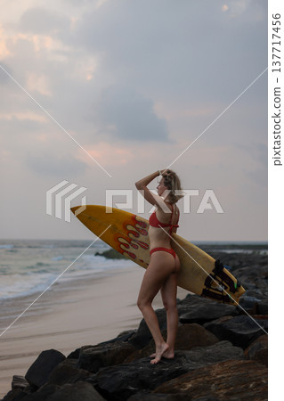 Beachside Surfer Enjoying Evening Sky. Evening Beach Surfer Gazing At Vibrant Sunset Colors In Sky Beachside Surfer Enjoying Evening Sky. Evening Beach Surfer Gazing At Vibrant Sunset Colors In Sky 137717456
