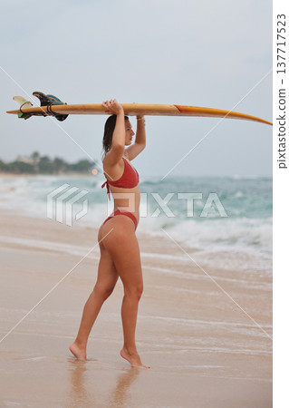 Woman Observes Ocean. Female Athlete Assesses Rolling Waves And Distant Horizon In Quiet Morning Mood Woman Observes Ocean. Female Athlete Assesses Rolling Waves And Distant Horizon In Quiet Morning Mood 137717523