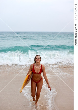 Woman Surfacing With Vibrant Energy. Energetic Woman In Red Bikini Running Through Splashes Of Water 137717531