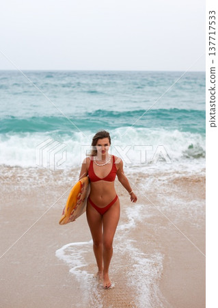 Beach Girl Smile. Lively Female Surfer In Red Bikini Navigating Incoming Waves With Joyful Enthusiasm Beach Girl Smile. Lively Female Surfer In Red Bikini Navigating Incoming Waves With Joyful Enthusiasm 137717533