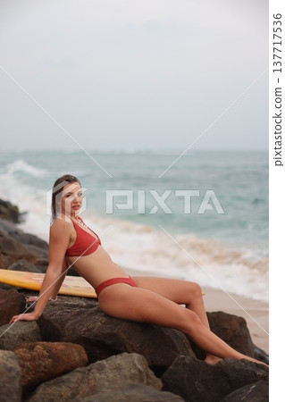 Tranquil Coastal Image Capturing Surfer Resting Amidst Rough Ocean Waves And Overcast Skies Tranquil Coastal Image Capturing Surfer Resting Amidst Rough Ocean Waves And Overcast Skies 137717536