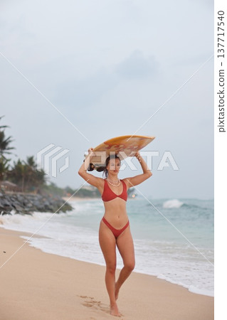 Confident Woman In Sunny Surf. Caucasian Woman Confidently Walks Towards Ocean Waves Along Beach Confident Woman In Sunny Surf. Caucasian Woman Confidently Walks Towards Ocean Waves Along Beach 137717540
