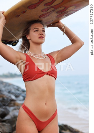 Dynamic Woman In Red Bikini Gazing Confidently Over Rocky Coastline With Wave Anticipation Dynamic Woman In Red Bikini Gazing Confidently Over Rocky Coastline With Wave Anticipation 137717550