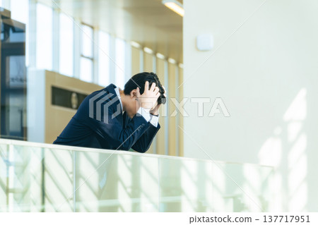 辦公大樓大廳裡一位鬱悶的男商人 辦公大樓大廳裡一位鬱悶的男商人 137717951