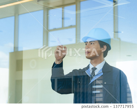 Male worker checking through glass inside a building Male worker checking through glass inside a building 137717955