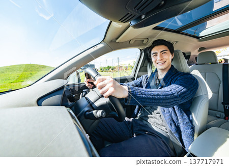 A scene in a car of a male driver driving a car with a smile A scene in a car of a male driver driving a car with a smile 137717971