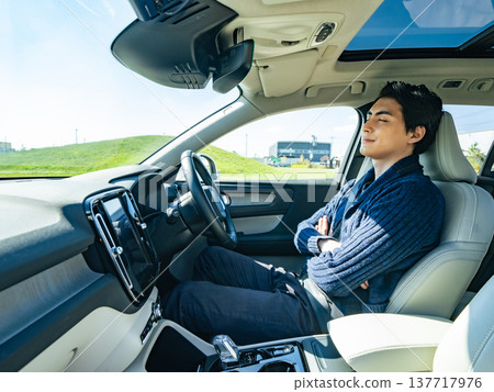 Male driver sleeping in the driver's seat of a car 137717976