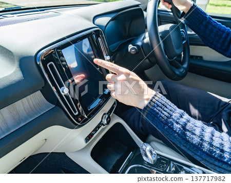 A driver touching the dashboard screen of a car A driver touching the dashboard screen of a car 137717982