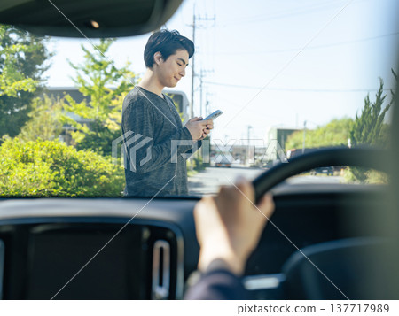 A man walking across in front of a car while holding his smartphone. 137717989