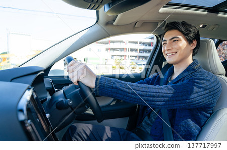 A scene in a car of a male driver driving a car with a smile A scene in a car of a male driver driving a car with a smile 137717997