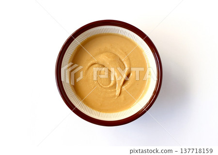 Homemade peanut butter ground in a mortar and pestle, viewed from directly above against a white background. Homemade peanut butter ground in a mortar and pestle, viewed from directly above against a white background. 137718159