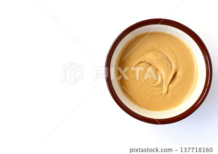 Homemade peanut butter ground in a mortar and pestle, viewed from directly above against a white background. 137718160
