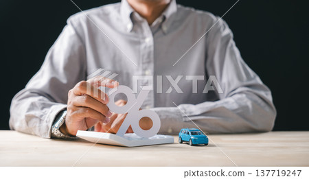 Hand holds percent symbol over calculator for car finance, interest rate, loan, auto sale, calculating price, insurance, tax, increase, for money management 137719247