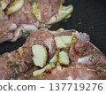 Cooking chicken thighs and garlic in a frying pan. 137719276