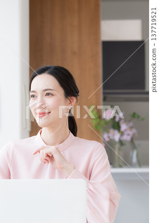 一位身穿粉紅色洋裝的美麗女子坐在辦公桌前使用電腦工作。 一位身穿粉紅色洋裝的美麗女子坐在辦公桌前使用電腦工作。 137719521