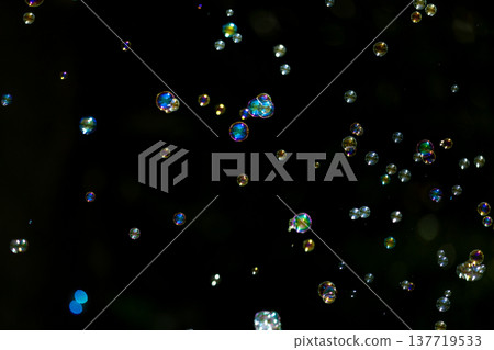 Rainbow-colored soap bubbles floating against a black background 137719533