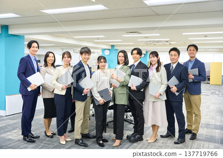 一大群商務人士，包括男性和女性，聚集在寬敞的辦公區域進行全身照拍攝。 137719766