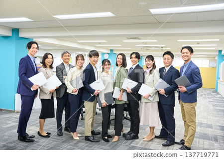 一大群商務人士，包括男性和女性，聚集在寬敞的辦公區域進行全身照拍攝。 137719771
