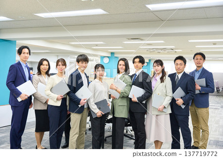 一大群商務人士，包括男性和女性，聚集在寬敞的辦公區域進行全身照拍攝。 137719772