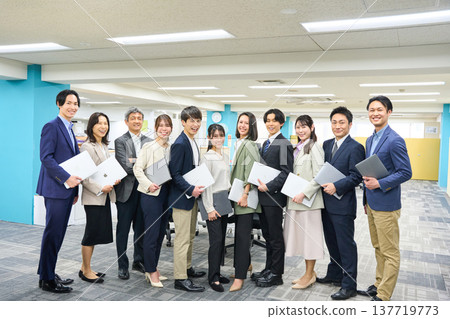 一大群商務人士，包括男性和女性，聚集在寬敞的辦公區域進行全身照拍攝。 137719773