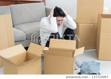 A man who hasn't finished packing for his move (cardboard boxes, tidying up, organizing) A man who hasn't finished packing for his move (cardboard boxes, tidying up, organizing) 137720067