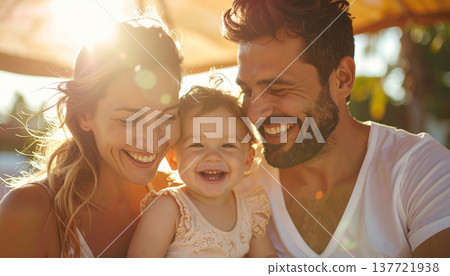 一家三口（母親、嬰兒、父親）在遮陽傘下歡笑。 137721938