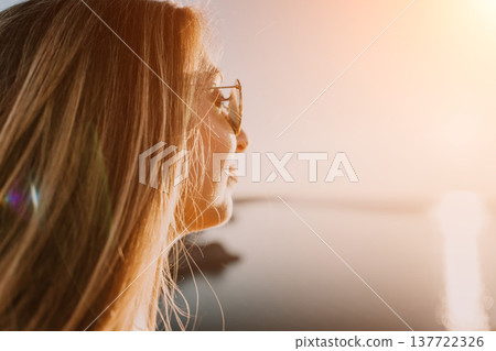 Woman sunset profile looking over the calm water with golden light during a peaceful summer vacation 137722326