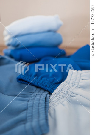 Clothes neatly folded in different shades on a wooden surface in a bright room Clothes neatly folded in different shades on a wooden surface in a bright room 137722595
