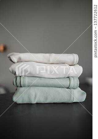 Stack of folded clothes on a dark surface with a plain background Stack of folded clothes on a dark surface with a plain background 137722612