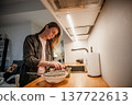 Woman prepares food in kitchen at home during afternoon while focused on meal 137722613