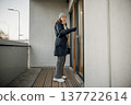 Woman standing at the door in winter clothing waiting for someone to answer the door at evening 137722614
