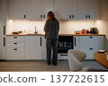 Woman standing in a modern kitchen preparing food early in the morning 137722615