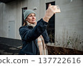 Woman takes selfie outside a modern building in cold weather during daytime 137722616