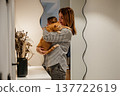 Woman holds orange cat in modern home interior during evening time 137722619