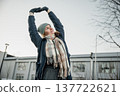 Young person stretches in cold weather outside a building during daytime in winter 137722621