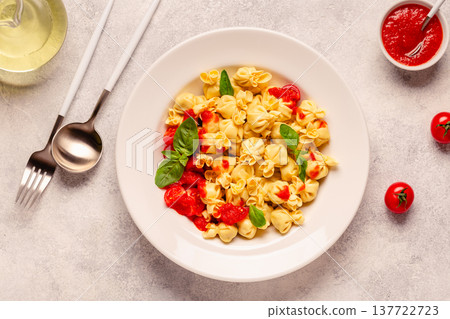 pasta in a plate with tomato sauce. 137722723