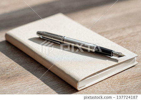工作空間圖片，圖中可見鋼筆放在筆記本和木桌上。 137724187