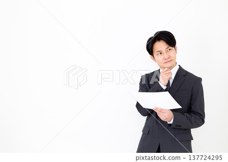 一位身穿西裝的中年商人正在仔細研究一張圖表。 137724295